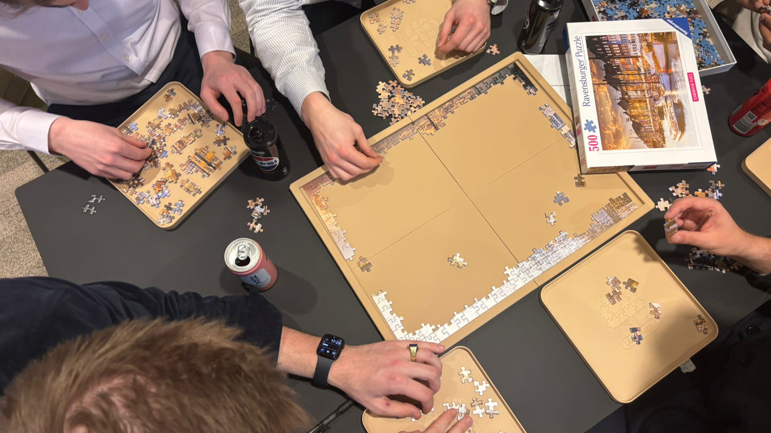 Group of people working on jigsaw puzzles at a table.